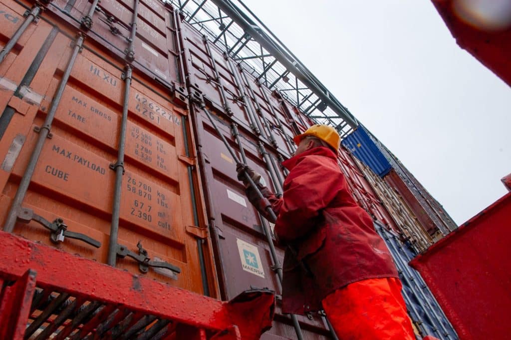 Worker inspecting and opening a shipping container during cargo security inspection at a freight terminal